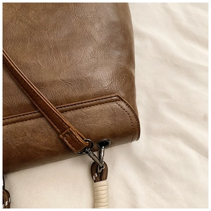 Detailed macro view of dark brown leather texture with fine stitching and metal hook
