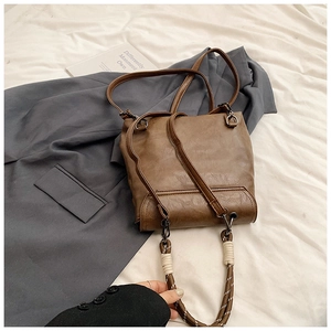 Macro detail of dark brown leather backpack with distinctive braided rope handle design