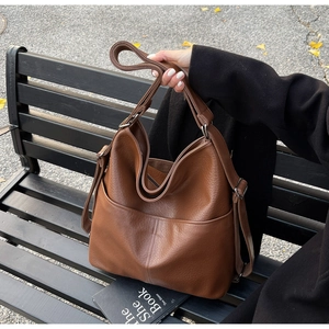 Gros plan sur le sac hobo en cuir marron montrant la texture et la poche latérale detail