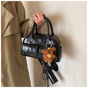 Détail du sac bowling en cuir verni noir avec boucles argentées et pendentif ours