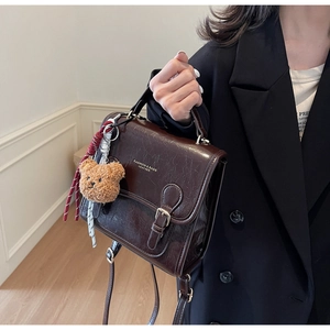 Detail view of vintage dark brown faux leather bag with bear charm and buckle strap