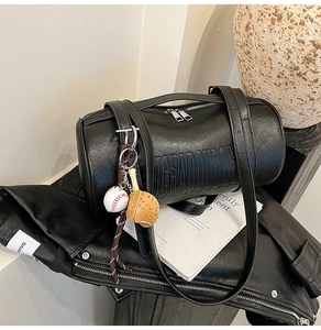 Detail of black Boston cylinder bag with embossed letters and sports themed charms