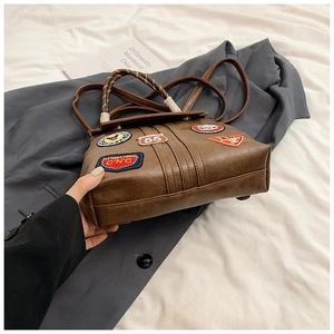 Detailed view of vintage brown leather handbag with retro patches and metal base rivets