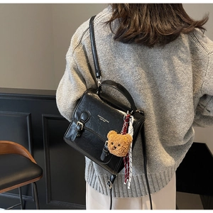 Detail view of black vintage leather mini square bag with cute brown bear charm