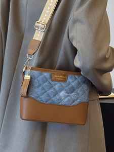 Blue denim quilted bucket bag with brown leather trim and wide woven strap for women