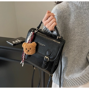 Detail of black wax leather backpack with bear charm and decorative scarf accessory
