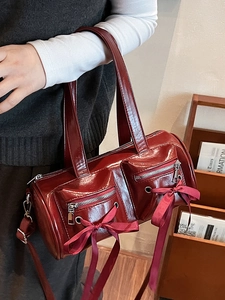 Sac à main cylindrique rouge foncé en cuir verni avec nœuds et bandoulière réglable