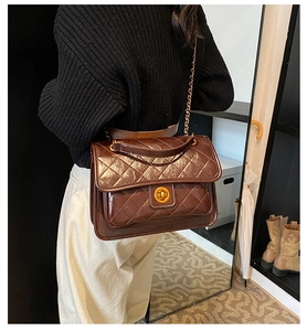 Detailed side view of brown quilted crossbody bag with gold chain and metal twist lock