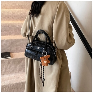 Détail du sac bowling en cuir noir brillant avec marquage chic et pendentif ours en peluche