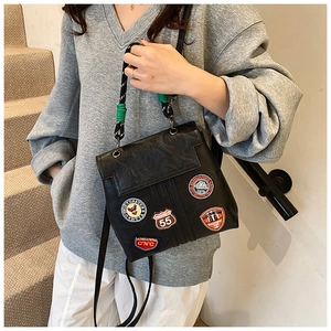 Detail view of black vintage bag with colorful embroidered badges and woven top handle