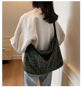 Detailed back view of a large plaid tote bag with wide strap on model in modern setting