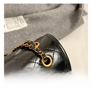 Macro shot of gold metal eyelets and leather chain strap on black quilted bag