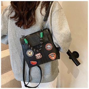 Close-up of vintage black PU leather bag with colorful embroidery patches and green knots