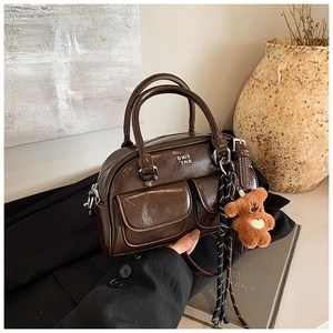 Détail d'un sac bowling vintage marron foncé brillant avec un petit ours en peluche
