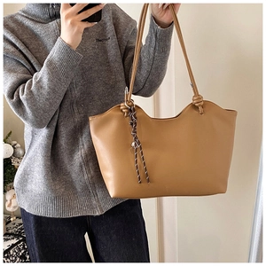 Detail showing caramel brown leather tote bag with unique knotted rope strap decoration