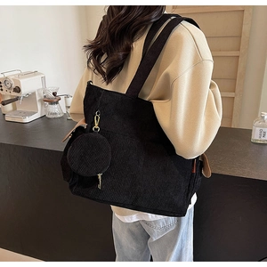 Detail view of black corduroy tote bag with small round coin pouch in a cafe setting