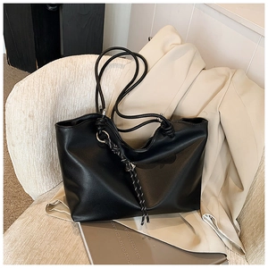 Close-up of black minimalist tote bag with silver ring hardware and woven rope detail