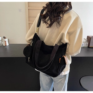 Detail of black corduroy tote bag with small round coin purse and wide strap on model