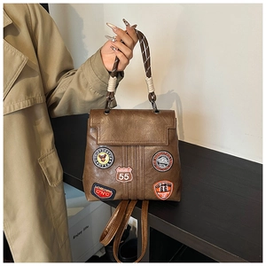 Detail of vintage brown PU backpack with retro patches and woven handles on a wooden table