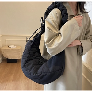 Detail of black quilted moon bag featuring ruffled shoulder strap and nylon texture