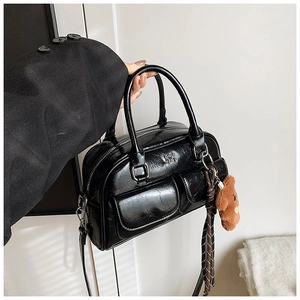 Détail du sac bowling en cuir noir avec poches cargo et breloque ourson en peluche