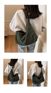 Close-up of green plaid wool tote bag featuring adjustable strap and spacious crescent shape