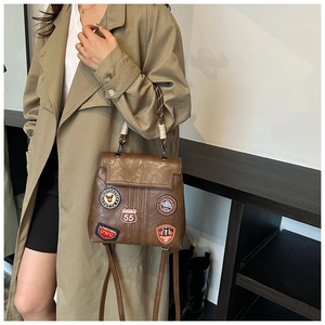 Detail of vintage brown leather backpack with colorful embroidered patches and braided handle