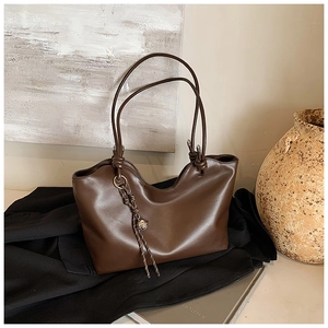 Detail of dark brown leather tote bag with braided handle and silver planet charm