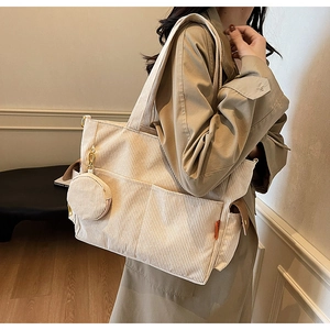 Detail view of beige corduroy tote bag with small round coin purse and side pocket