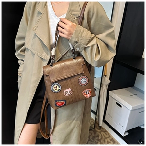 Detail view of vintage brown faux leather backpack with retro embroidery patches