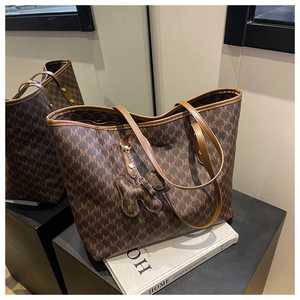 Detailed close-up of a large brown monogram tote bag with leather handles and pendant charm