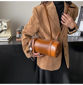 Brown vintage cylinder bag with logo embossing and a baseball glove charm detail