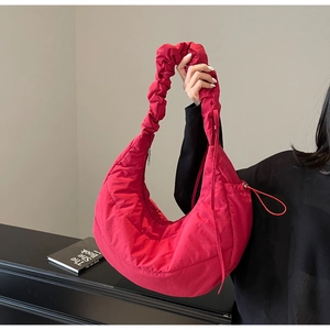 Detail of red quilted puffer shoulder bag with ruched strap and half-moon design