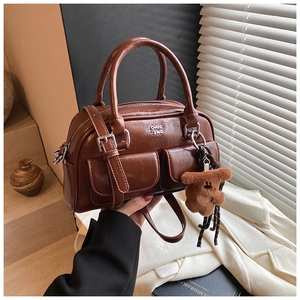 Détail du sac bowling rétro marron avec logo argenté et breloque ours en peluche