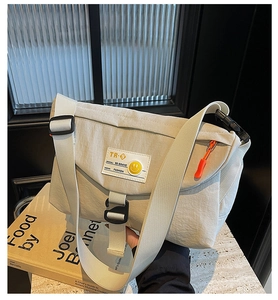 Dettaglio borsa a tracolla in nylon crema con tracolla regolabile e cerniera arancione