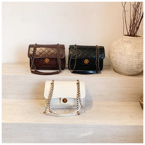 Three elegant quilted leather bags in brown, black, and white with gold chain straps