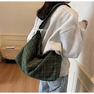 Close-up of green checkered canvas tote bag with wide strap in retro casual style