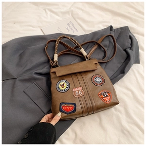 Detailed shot of brown vintage backpack with embroidered patches and woven handle detail