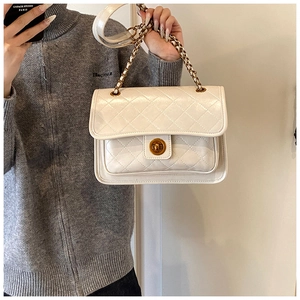 Detailed view of white quilted shoulder bag with gold metal twist lock and chain strap