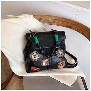 Close-up of black retro backpack featuring vintage patches and woven rope handle details