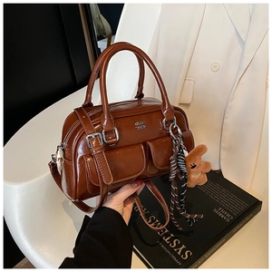 Détail du sac à main rétro en cuir marron avec breloque ourson et décoration de foulard