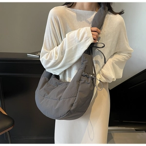 Detailed macro view of gray quilted crescent crossbody bag with drawstring bow details