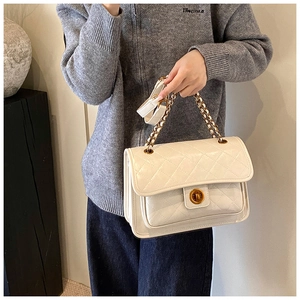 Detailed view of white quilted faux leather bag with golden twist lock and chain strap
