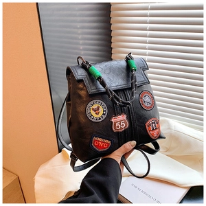 Close-up of black retro backpack with colorful embroidered badges and green knotted handle