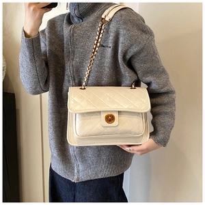 Macro detail of white quilted crossbody bag featuring gold twist lock and chain strap