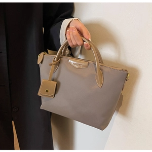 Detail of taupe nylon tote bag with glossy patent leather handles and square coin pouch