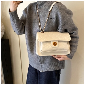 Close-up of white quilted leather texture with gold metal lock on luxury chain bag