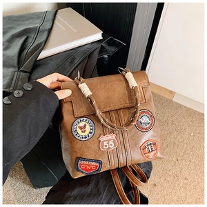 Close-up of vintage brown leather backpack featuring colorful embroidered patches and rope handles