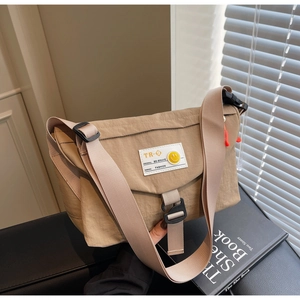 Dettaglio della borsa a tracolla in nylon kaki con etichetta smiley e zip arancione