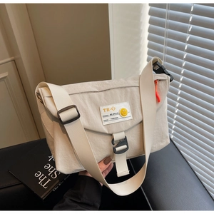 Dettaglio della borsa messenger beige con chiusura a fibbia e ricamo smiley giallo vivace